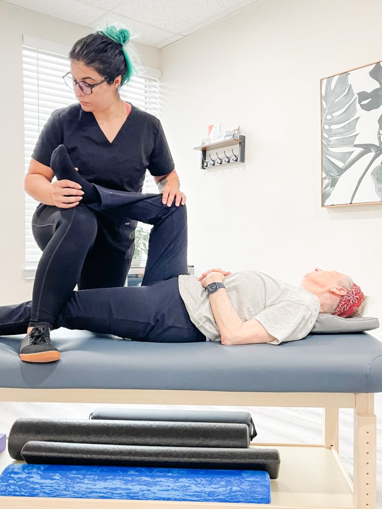Sharifa guiding a client through an assisted stretch on a treatment table